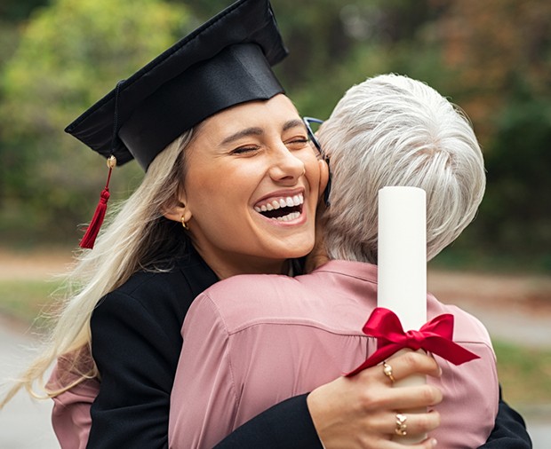 Young graduate female hugs older woman